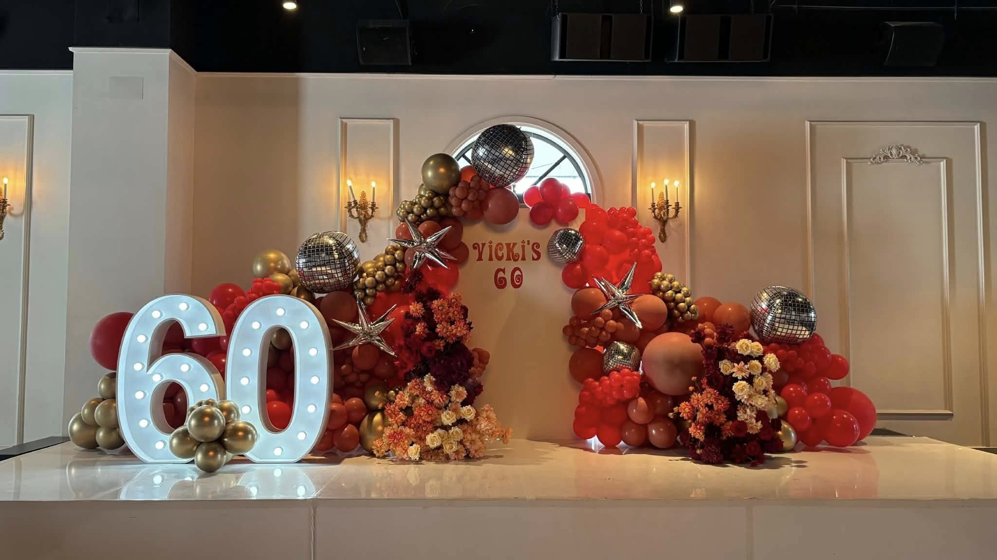 Sixtieth birthday disco setup with gold and red balloon styling