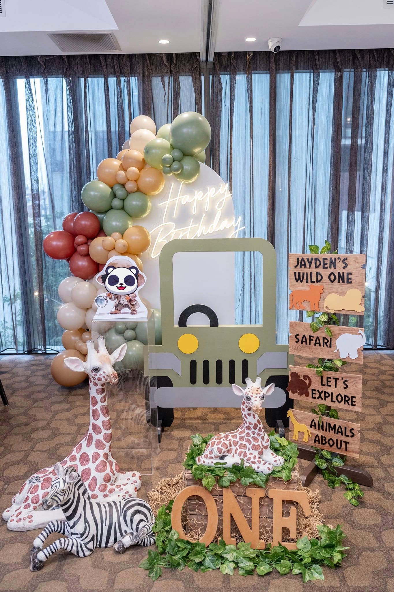 Safari-themed children's birthday with balloons, animals, signage, and plaque