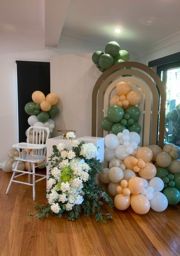 Nature-inspired highchair setup with balloons, plaque, and florals