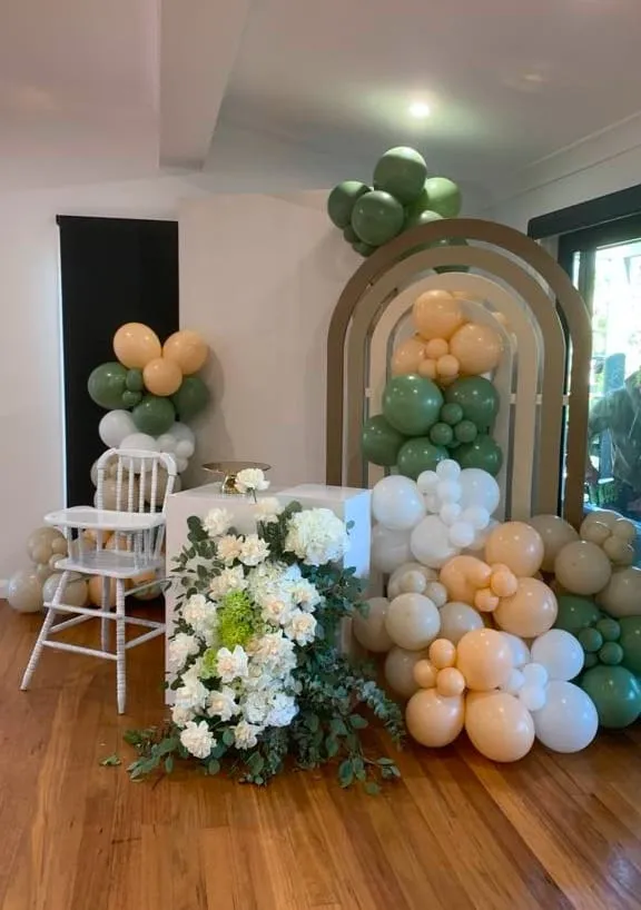 Nature-inspired highchair setup with balloons, plaque, and florals